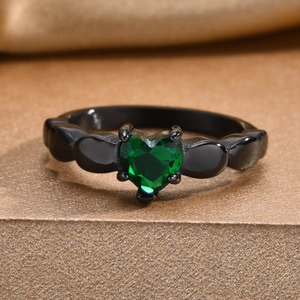 Vue macro d'une zircone verte en forme de cœur sertie sur une bague en métal noir poli