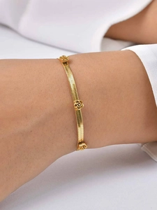 Close-up of gold snake chain bracelet with rose floral charms on a woman's wrist