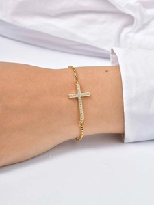 Close-up of a gold adjustable chain bracelet with a sparkling crystal cross on a wrist