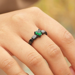 Bague cœur plaquée noire avec zircon vert, vue macro portée sur la main du mannequin