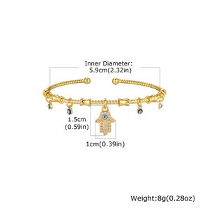 Detail of gold evil eye bangle with Hamsa Hand charm and white zircon micro-inlay