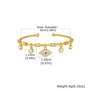 Detail of twisted gold bangle featuring blue evil eye and zircon round pendants