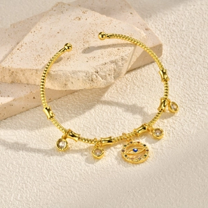 Detailed close-up of a gold-plated evil eye cuff bracelet with sparkling zircon charms