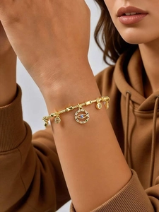 Close-up of golden evil eye charm bracelet with colored zircons worn on model wrist