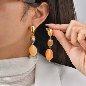 Detailed close-up of geometric resin drop earrings in gold, coffee, and orange tones