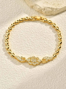 Macro detail of 24K gold floral bracelet with sparkling zircon stones on stone surface