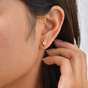 Gros plan d'une boucle d'oreille ours en zircon cœur portée à l'oreille, finition dorée