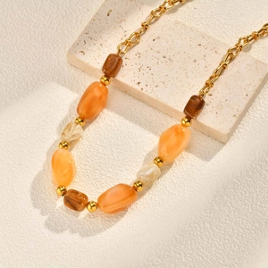 Detail of bohemian gold chain necklace with amber and marble resin beads on stone