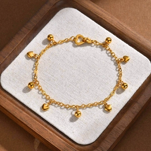 Elegant gold heart and bead charm bracelet in stainless steel on a wooden display