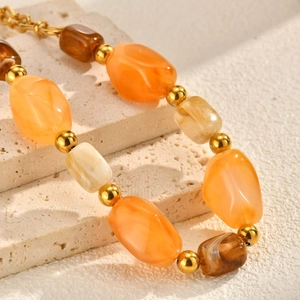 Macro detail of irregular resin beads with gold metal spacers on a textured stone surface