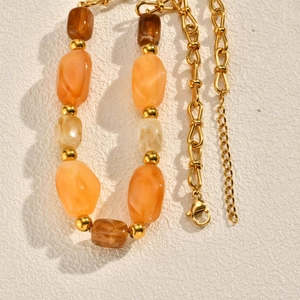 Close-up of vintage resin bead necklace with amber tones and gold-plated chain detail