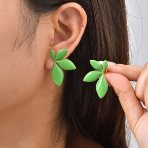Close-up of green leaf stud earrings in stainless steel on ear and held by hand
