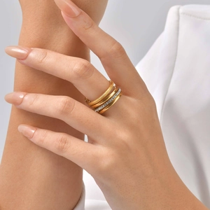 Close-up of a stacked gold ring set featuring sparkling pavé crystals and frosted finish