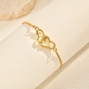 Detail of interlocking heart bracelet with white zircons on a golden box chain