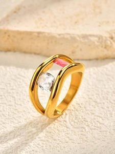 Detailed view of wave-shaped gold ring with round clear stone and pink zircon accent