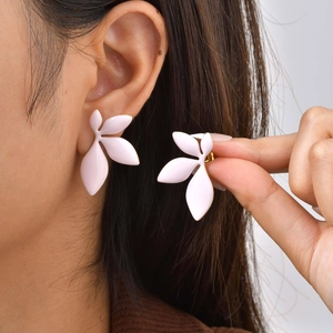 Macro view of gold-rimmed pink leaf earrings showing delicate texture and elegant design