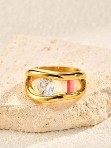 Detailed close-up of wavy gold ring featuring sparkling clear and pink zircon stones