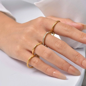 Detail view of four-piece gold stainless steel rings with sparkling crystals on hand