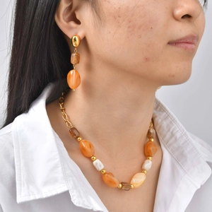 Detail of amber resin bead necklace and matching earrings set with gold metal accents