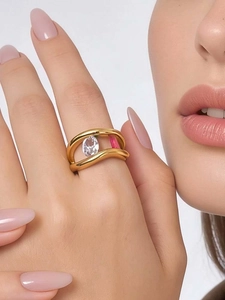 Detail of gold wave ring with oval zircon and pink enamel inlay on finger