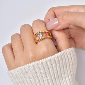 Detail of gold wave ring featuring oval white and rectangular pink zirconia on hand