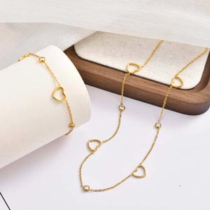 Détail de colliers et bracelets cœur doré ajouré sertis de zircons sur supports blancs