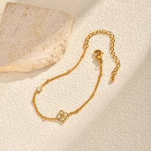 Détail du bracelet trèfle doré avec zircons blancs sur fond de pierre naturelle