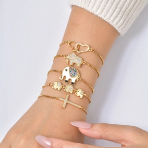Adjustable gold plated bracelet set featuring cubic zirconia elephant and cross charms