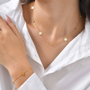 Parure collier et bracelet en acier doré avec fleurs évidées et zircons brillants