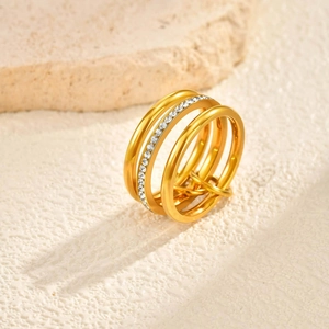 Bague multicouche en acier doré avec strass sur un support en pierre texturé