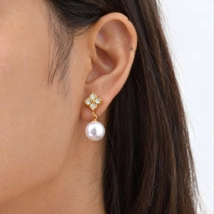 Détail des boucles d'oreilles en perles trèfle avec clous dorés portées par un mannequin