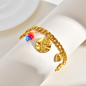 Détail du bracelet à maillons dorés avec pièce de rose embossée, cœur et perles colorées