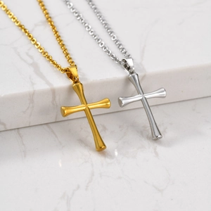 Polished gold and silver cross pendants on minimalist chains over white marble surface