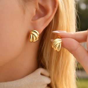 Detailed close-up of golden stainless steel hoop earrings with vertical wavy texture