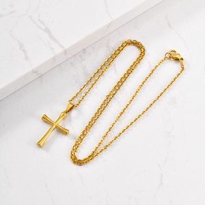 Detailed shot of a gold cross pendant on a cable chain against white marble