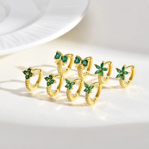 Detail of four pairs of gold bow and clover earrings with green cubic zirconia stones