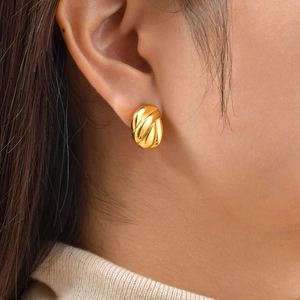 Macro shot of gold teardrop earrings with twisted texture and polished metallic finish