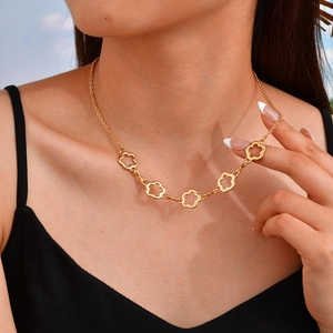 Dettaglio della collana placcata oro 18K con ciondoli a quadrifoglio su un abito nero