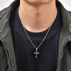 Detailed close-up of a polished silver stainless steel cross pendant on a twist chain necklace