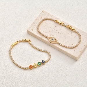 Détail de bracelets dorés avec oeil maléfique et fleurs de trèfle colorées en zircon