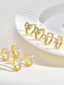 Macro shot of gold earring set with white zircons in bow and flower patterns