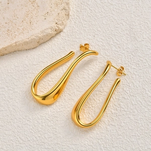 Close-up of golden U-shaped curved earrings with polished finish on white textured background