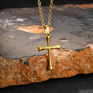 Detailed view of a polished gold cross pendant on a textured natural stone background
