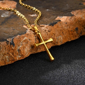 Detail of gold cross pendant on a textured rock with a high-quality twist chain