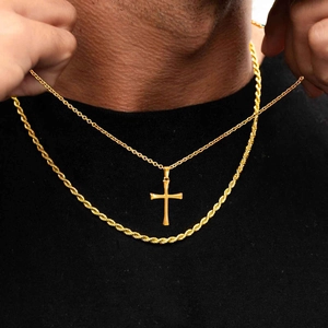 Detail of layered gold rope chain and minimalist cross pendant necklace for men