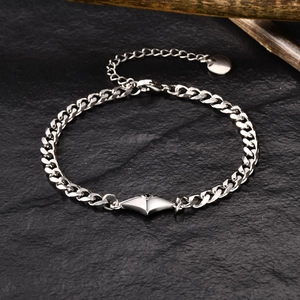Detail of silver Cuban link bracelet with diamond charm on natural black stone