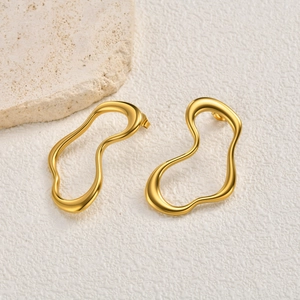 Detailed close-up of golden fluid-shape stainless steel earrings with glossy finish