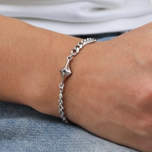 Detail of silver Cuban chain bracelet with a star motif and black stone on a male wrist