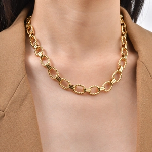 Detail of chunky gold cable chain necklace with textured oval links on a model