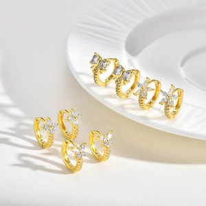 Golden earrings set with cubic zirconia featuring bow and floral designs on ceramic